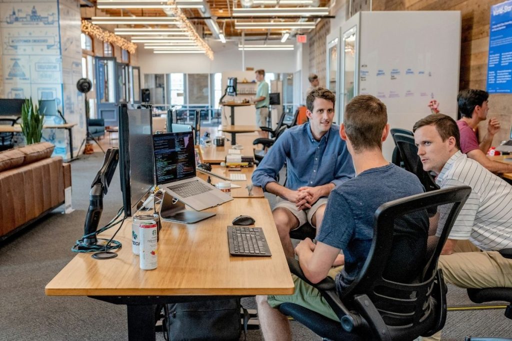 Photo d’un dirigeant en early stage échangeant avec son équipe dans un open space, illustrant le coaching de dirigeant pour startups